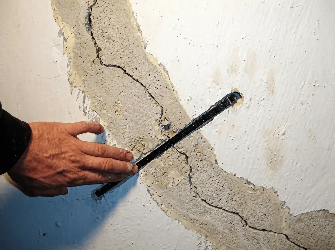 A wall with a large crack is being inspected by a professional in Tempe, AZ